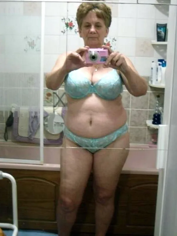 Personne en lingerie bleue prenant un selfie dans un miroir de salle de bain